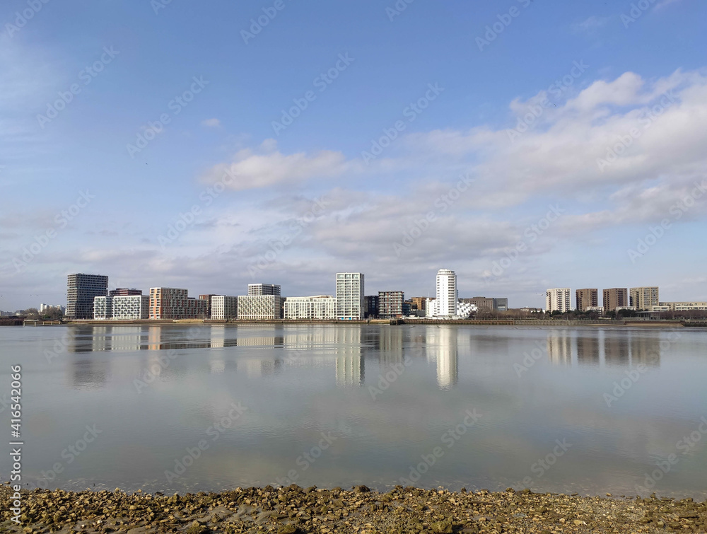 Greenwich Peninsular Thames path shoreline view of riverside homes with beautiful reflections in the water Greenwich Peninsular Thames path shoreline view of riverside homes with beautiful reflections in the water