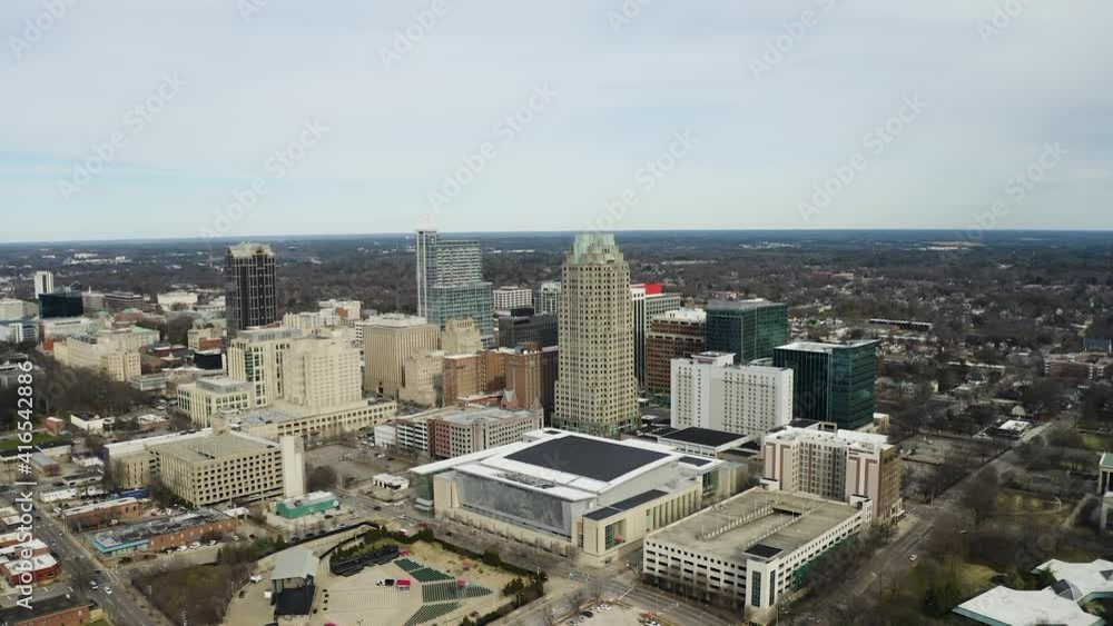 Giant screen on the outside of a shopping center in downtown Raleigh with the high buildings in the skyline in the background on a partly cloudy day. Drone shot dolly high angle shot Giant screen on the outside of a shopping center in downtown Raleigh with the high buildings in the skyline in the background on a partly cloudy day. Drone shot dolly high angle shot