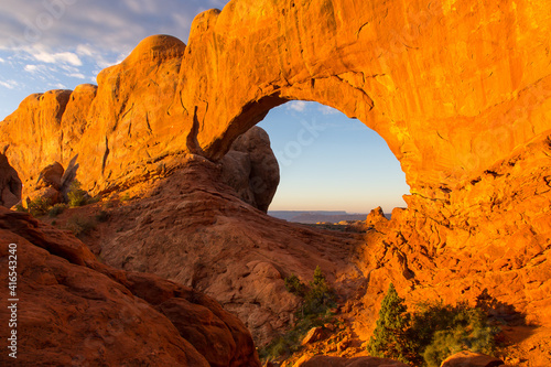 Horizontal view of stunning large red sandstone monument with huge window seen at sunrise in Arches National Park, Utah, USA