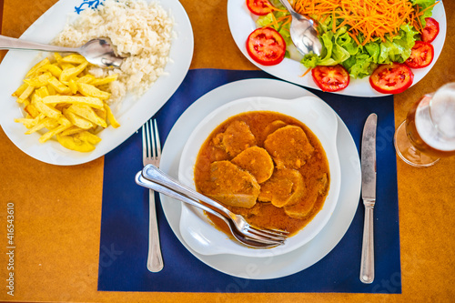 Traditional food from Alentejo - cow's tongue in a sauce served with salad, rice and french fries, Portugal photo