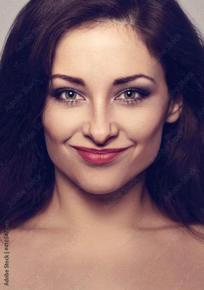 Beautiful perfect natural smiling woman with brown hair and bright makeup looking happy on grey background with empty copy space. Closeup Beautiful perfect natural smiling woman with brown hair and bright makeup looking happy on grey background with empty copy space. Closeup