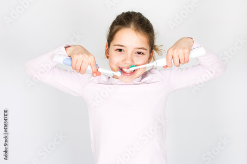 Young girl can´t decide between sonic and rotating oscillating toothbrush isotated on white background. Oral care and white teeth concept with copy space.