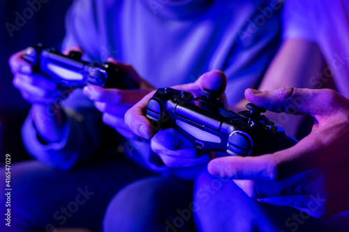 friends playing console video games. controller in hands closeup. neon lights photo