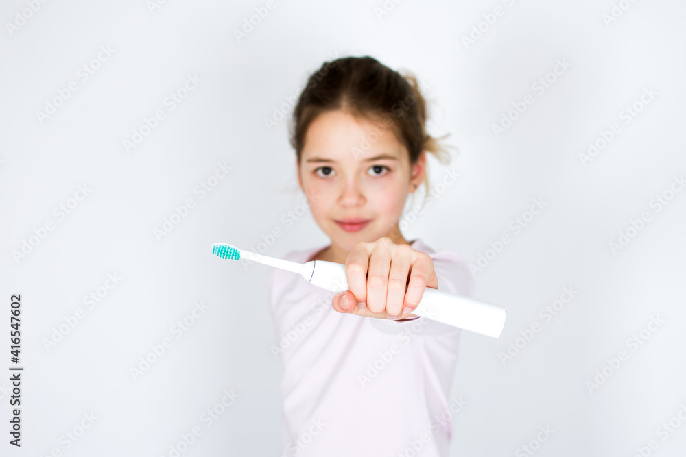 Child holding and showing sonic electric tooth brush isolated on white background. Oral hygiene and white teeth concept with copy space. Child holding and showing sonic electric tooth brush isolated on white background. Oral hygiene and white teeth concept with copy space.