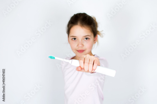 Child holding and showing sonic electric tooth brush isolated on white background. Oral hygiene and white teeth concept with copy space.