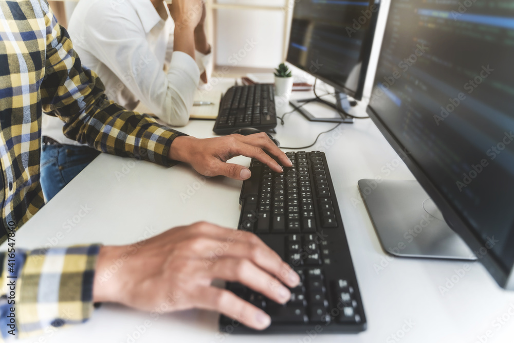 programmer writing program code with two monitors and working on a new software or hacker programming developing software applications in the office. programmer writing program code with two monitors and working on a new software or hacker programming developing software applications in the office.