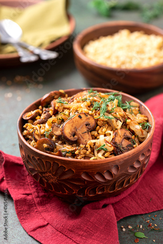 Spicy bulgur with mushrooms, onions, dill, and cumin in a bowl close-up. Bulgur stewed with mushrooms. Arabic cuisine, vegan and vegetarian food.