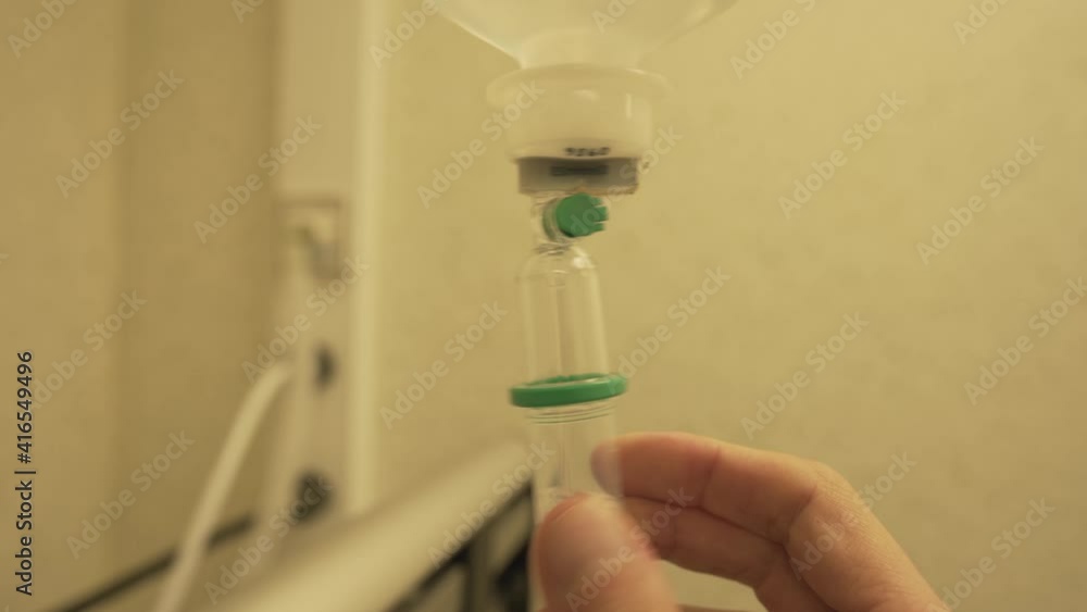 Close view of medical plastic giving set with doctor hand adjusting treatment fluid for patient in hospital during coronavirus pandemia Close view of medical plastic giving set with doctor hand adjusting treatment fluid for patient in hospital during coronavirus pandemia