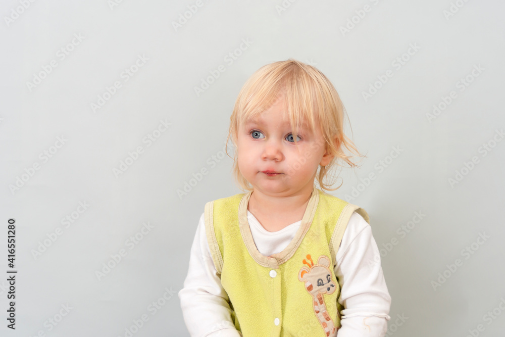 Surprised child on a gray background stands and looks to the side. Surprised child on a gray background stands and looks to the side.
