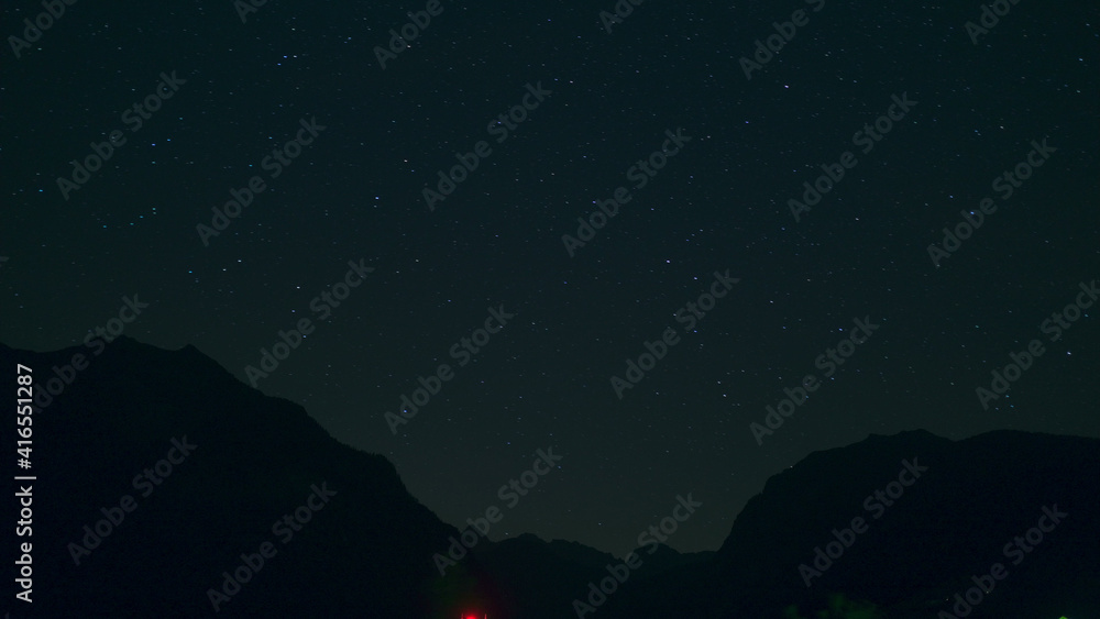 Fototapeta premium Time lapse of Night landscape with mountains and stars.