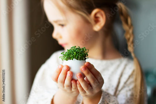 Little girl holding cress saladin eggshell in her hands