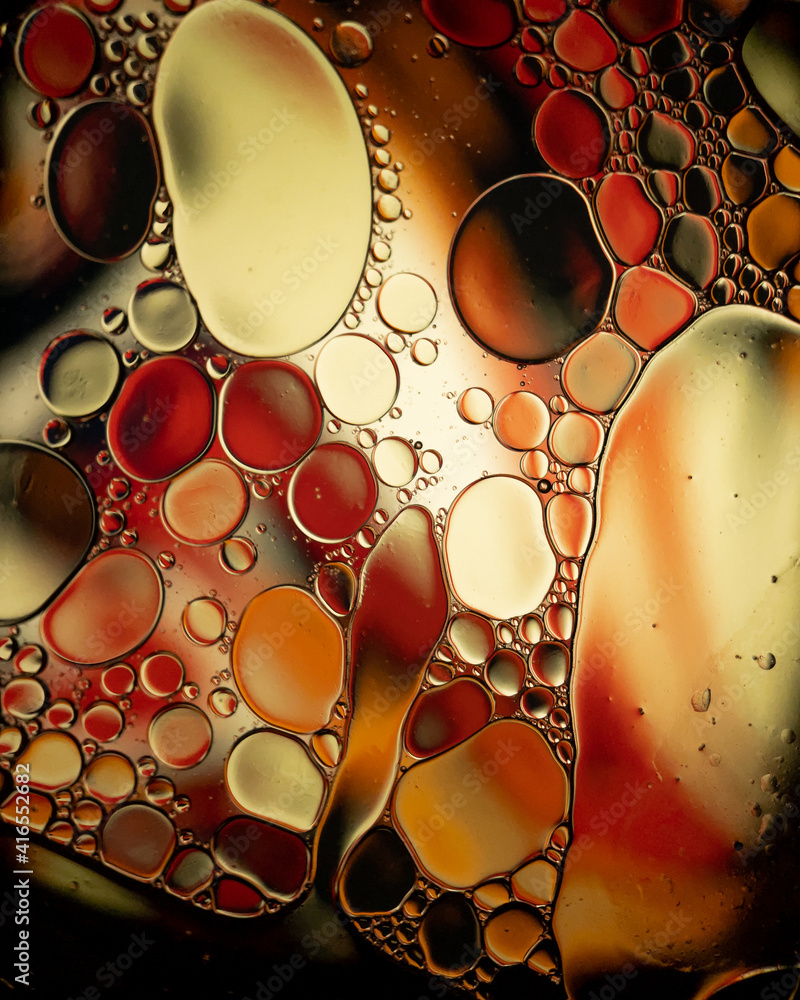 Oil drop bubbles on a water surface abstract with an orange and yellow soft background