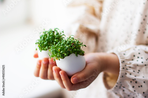 little girl holding cress saladin  eggshell in her hands	