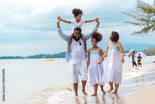 Happy African American family with African American father / asian mother and mixed race kids walking on the beach, thaliand photo