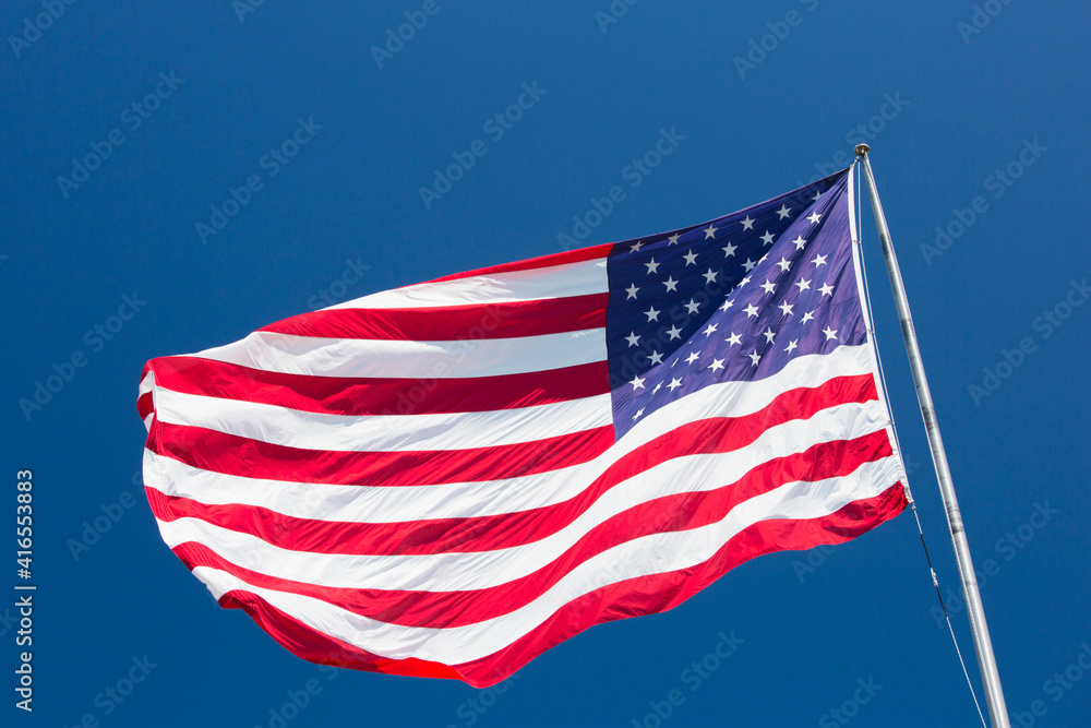 Giant US flag flying beneath a deep blue sky above Truman Avenue, Old Town, Key West, Florida Keys, Florida, United States of America, North America