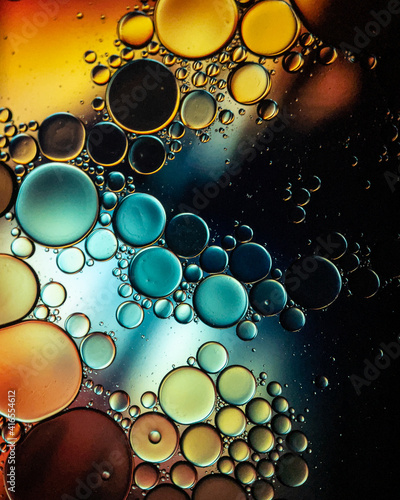 Oil drop bubbles on a water surface abstract with an aqua blue and pink swirl background