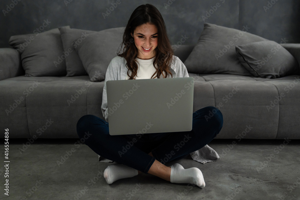 Happy smiling woman sitting on couch and using laptop Happy smiling woman sitting on couch and using laptop