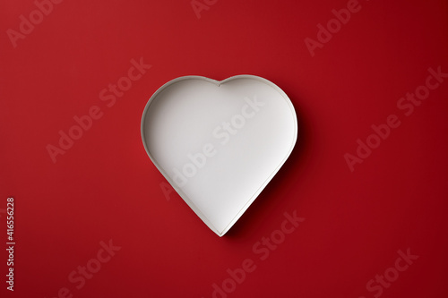 An empty, white heart-shaped box on a red background. 