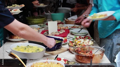 People helping themselves at a buffet like potluck sharing food