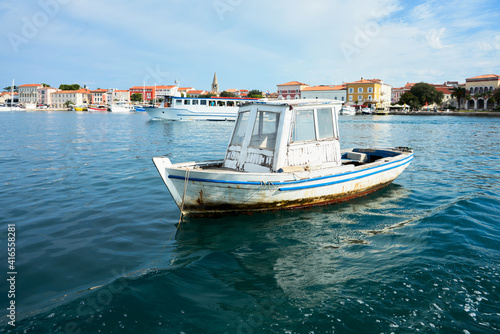 Funny old boat in the water area of Porec, Croatia. In the background, the old town embankment. Copy space.