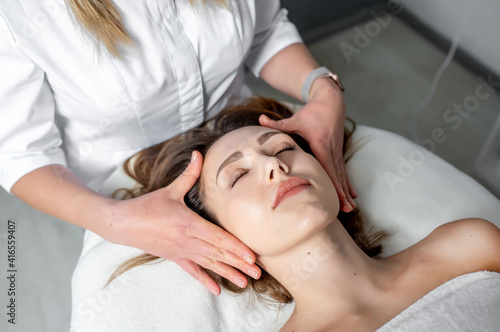 Facial massage of young woman receiving spa massage in beauty spa. Cosmetology.