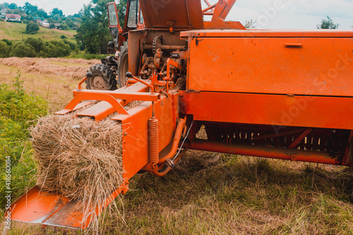 Canvas Print The process of harvesting hay for cattle, a tractor making bales in the field, old machinery