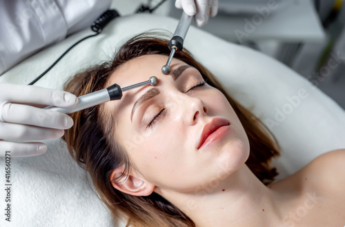 Young Woman At Spa Clinic Receiving Facial Stimulating Treatment. Close up of a young female face during microcurrent therapy.