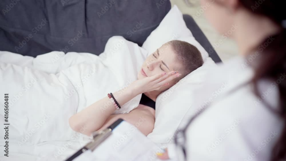 High angle view of woman complaining cancer relapse symptoms to female doctor taking medical history. Portrait of exhausted young sad Caucasian patient lying on couch talking and gesturing. High angle view of woman complaining cancer relapse symptoms to female doctor taking medical history. Portrait of exhausted young sad Caucasian patient lying on couch talking and gesturing.