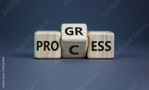 Process and progress symbol. Turned a wooden cube and changed the word 'process' to 'progress'. Beautiful grey background, copy space. Business, process and progress concept.