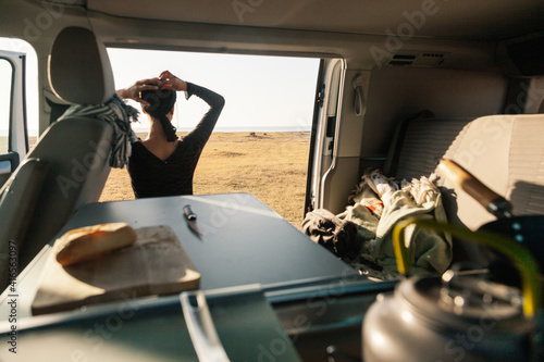 A young woman having breakfast in her caravan observing a good view of the beach photo