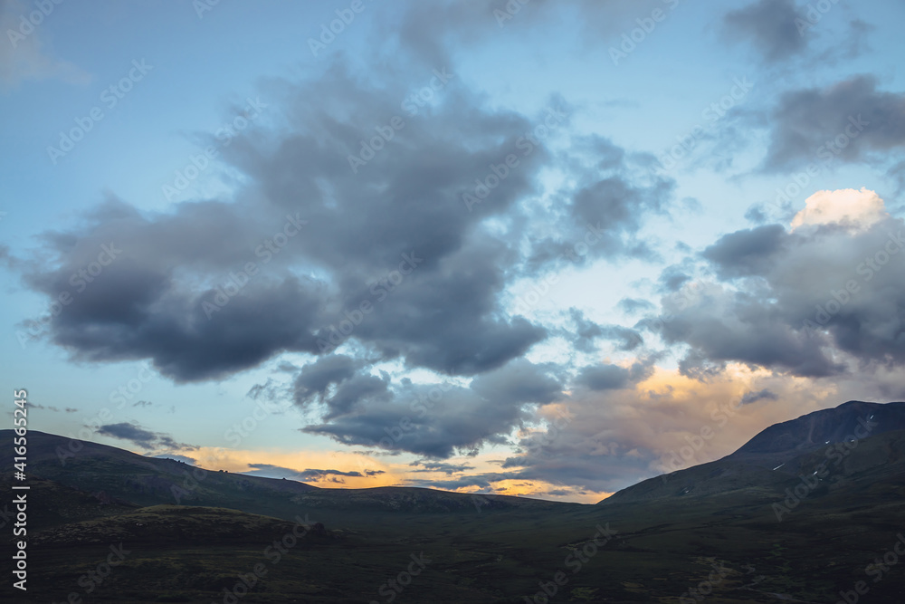 Beautiful mountain scenery with golden dawn light in cloudy sky. Scenic mountain landscape with illuminating color in sunset sky. Silhouettes of mountains on sunrise. Gold illuminating sunlight in sky Beautiful mountain scenery with golden dawn light in cloudy sky. Scenic mountain landscape with illuminating color in sunset sky. Silhouettes of mountains on sunrise. Gold illuminating sunlight in sky