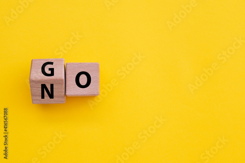 Papier peint cubes turning message NO to GO on paper yellow background