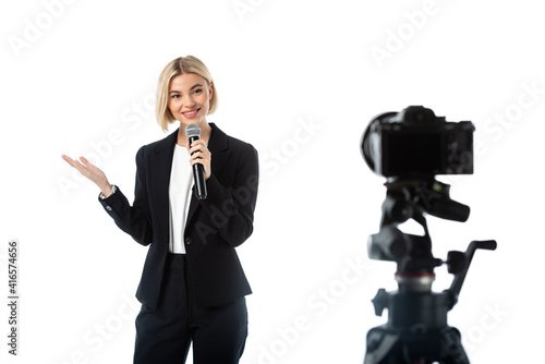 Photography cheerful broadcaster with microphone pointing with hand near digital camera on b