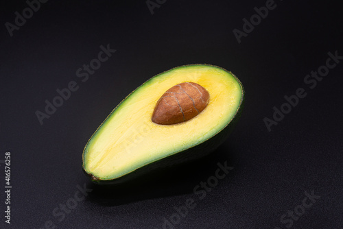 Half an avocado with a bone on a black background