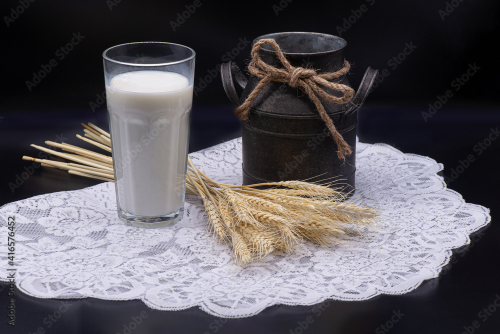 Composition of glass of milk, wheat, an old jug on a white tablecloth