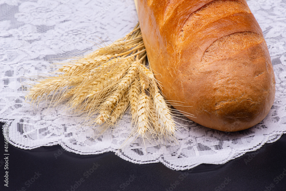 Composition of wheat, white bread on white tablecloth