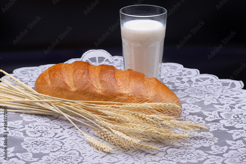 Composition of glass of milk, wheat, white bread on a white tablecloth