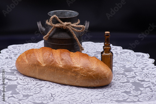 Obraz na płótnie Composition of white bread, small bottle and old jug on white tablecloth on black background w salonie