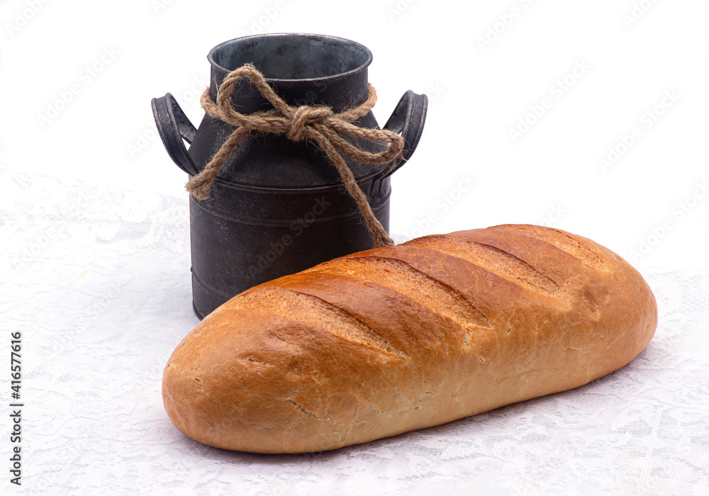 Composition of white bread and old jug on a tablecloth on white background