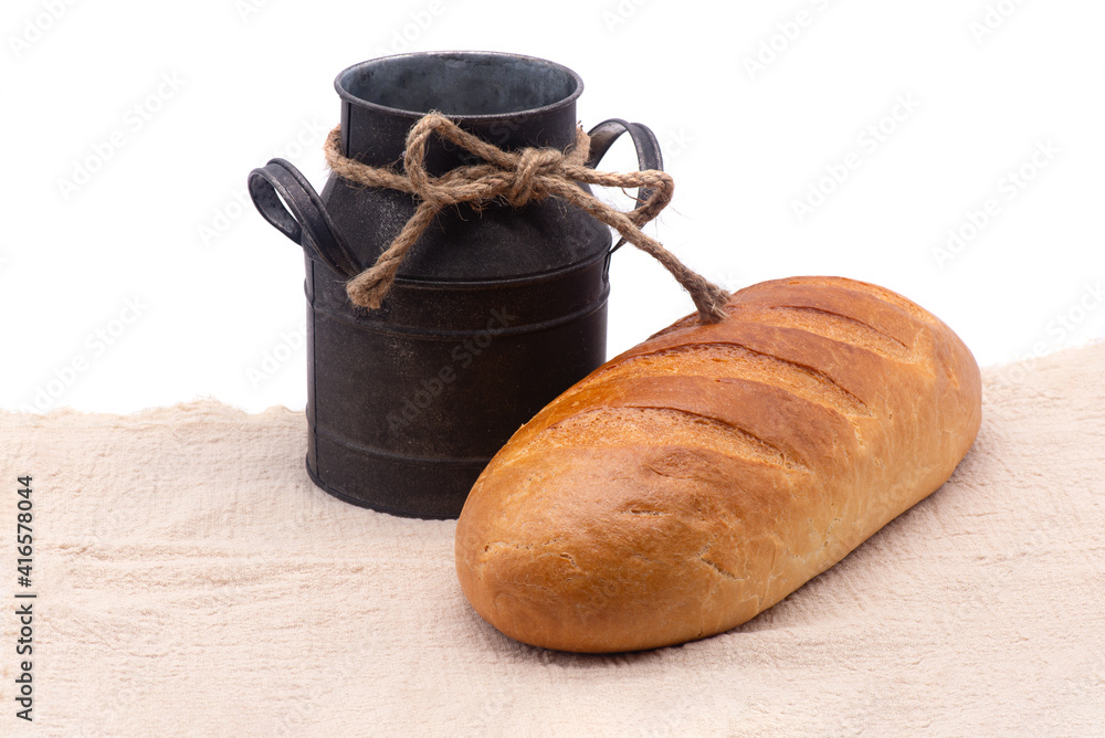 Composition of white bread and old jug on a tablecloth on white background
