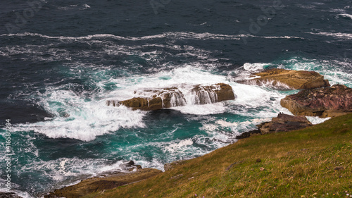 Stoer lighthouse view on wild ocean waves rocks