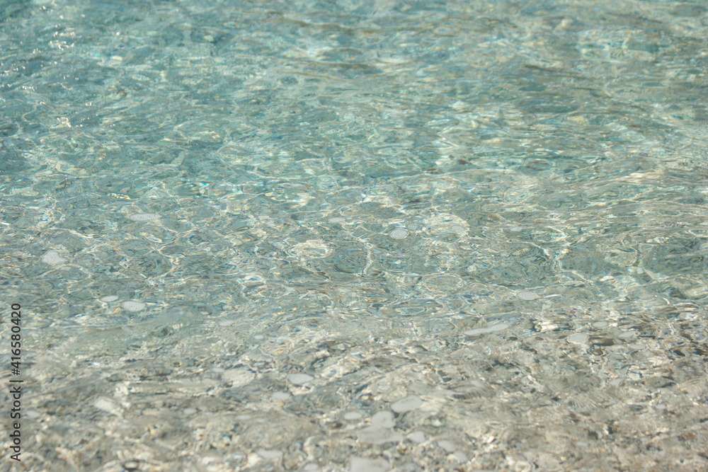 Crystal clear shallow sea water. Pebbles in shallow water on a beach. Seabed background. Crystal clear shallow sea water. Pebbles in shallow water on a beach. Seabed background.