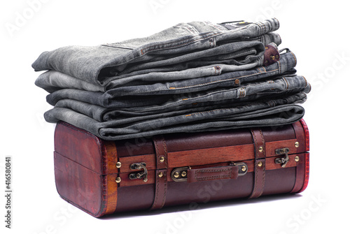 Obraz na płótnie Stack of gray jeans on a brown retro suitcase on white background w salonie