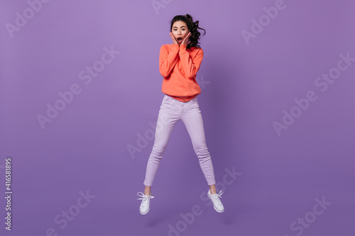 Amazed asian woman looking at camera. Studio shot of jumping surprised chinese girl.