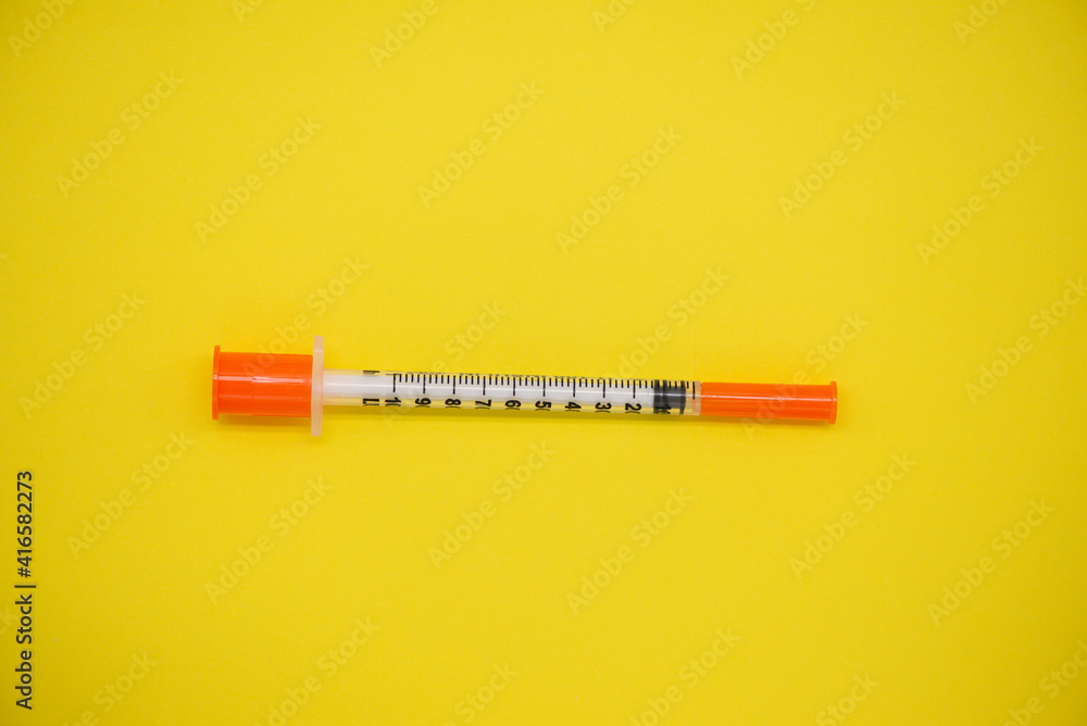 Insulin syringe on a yellow background