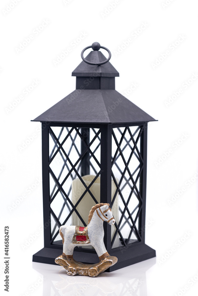 Glass lamp with a candle inside and toy clay horse on a white background