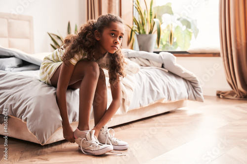 Girl tying shoelace and getting ready for walk or going to school photo