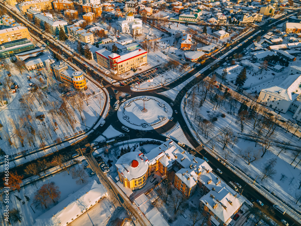 Fototapeta premium Aerial view of roundabout road with circular cars in small european city at winter sunset