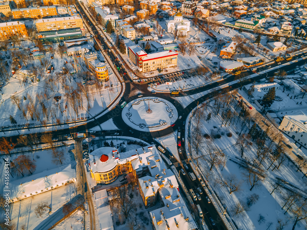 Fototapeta premium Aerial view of roundabout road with circular cars in small european city at winter sunset