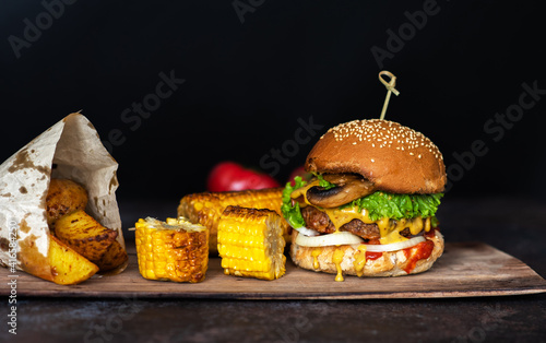 Food background of grilled hamburger on wooden board.Delicious fresh tasty homemade beef burger with cutlet cheese and ketchup. Craft beef burgers with vegetables.